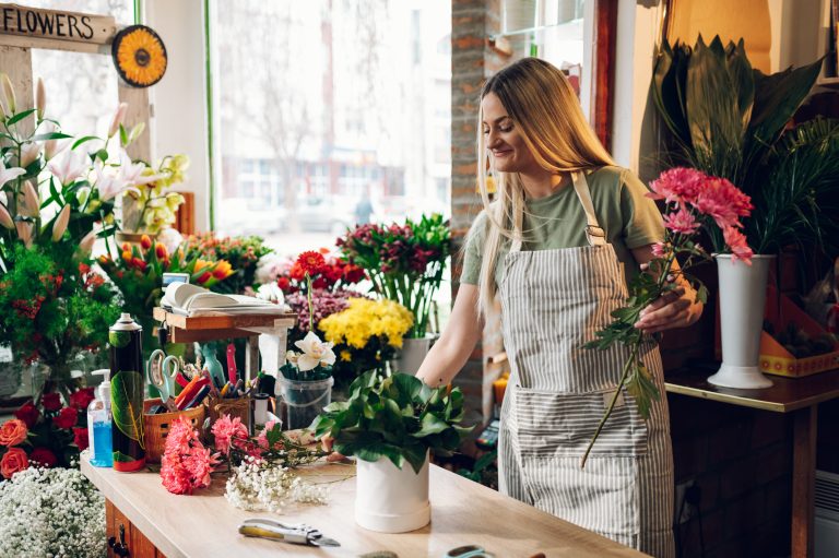 Florist woman creating flower arrangement in a round box